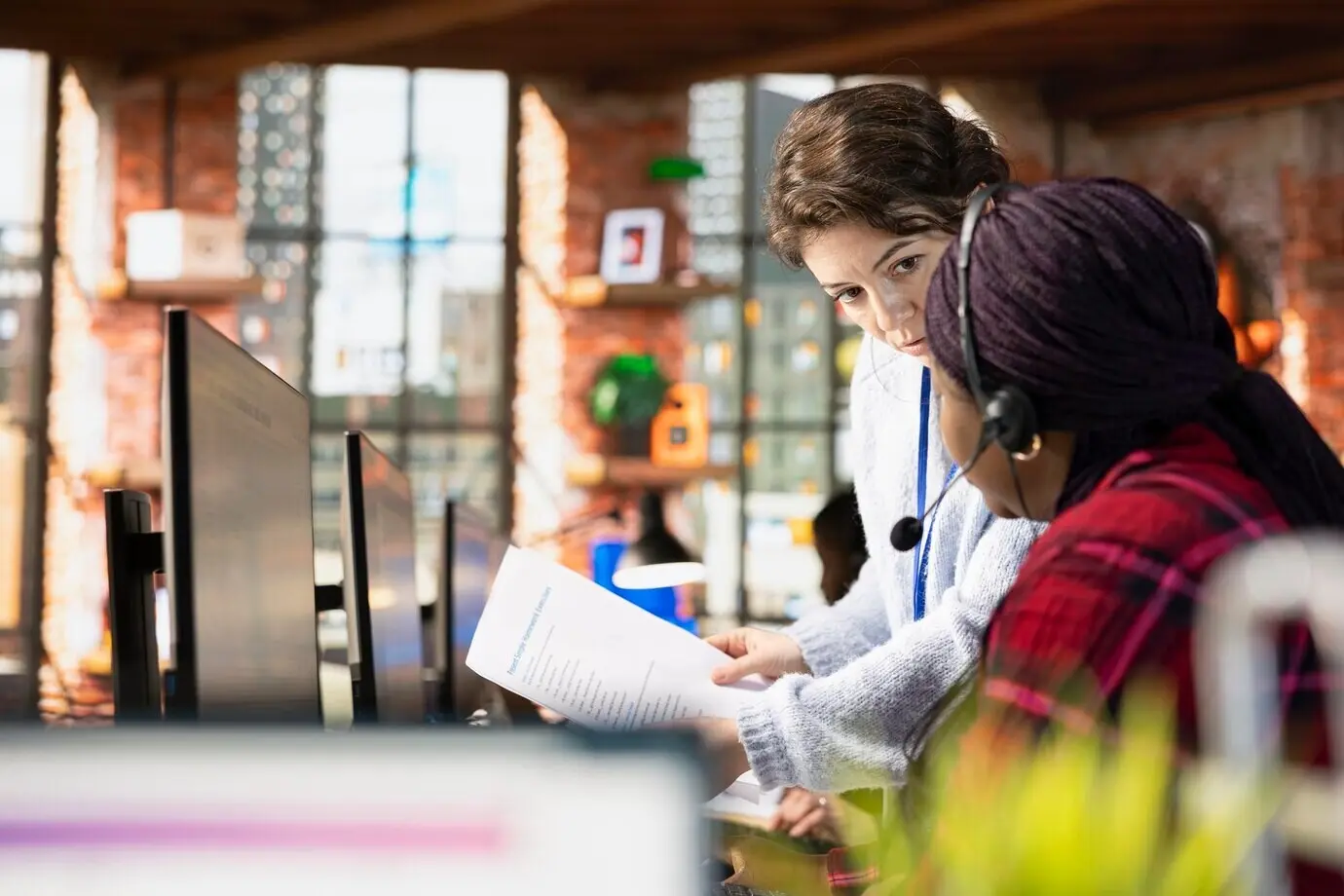 Специалист по онбордингу колл-центра просматривает бумажные документы вместе с сотрудником.